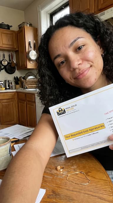 Customer holding Mail Gold Online appraisal kit at home